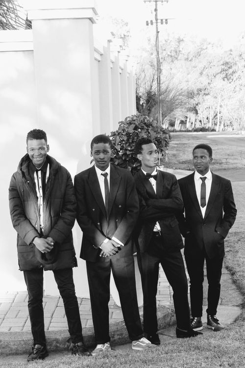 Free Four young men in suits posing outdoors in black and white. Stock Photo