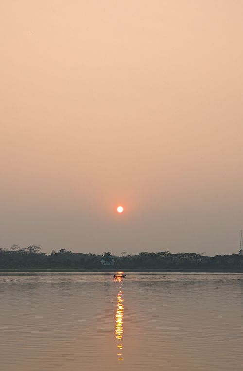 Free Peaceful sunset reflecting over a tranquil river with silhouette of distant trees. Stock Photo