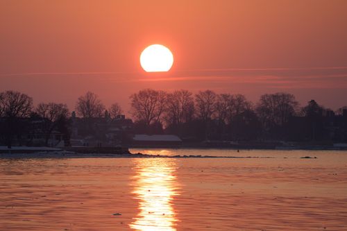Free A captivating winter sunrise over Stamford Harbor with a warm orange glow reflecting on the icy waters. Stock Photo