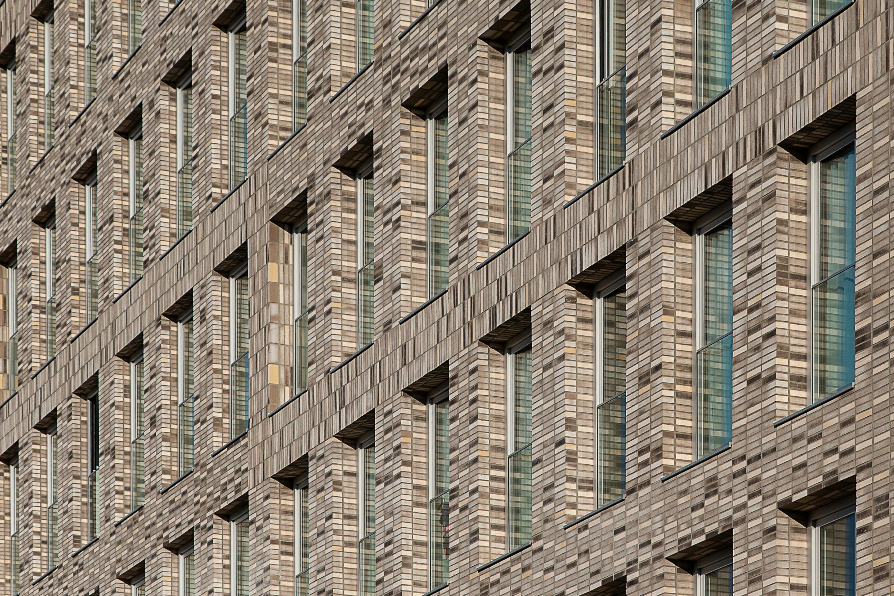 Free Close-up of a modern building's brick facade with regular windows, displaying architectural symmetry. Stock Photo