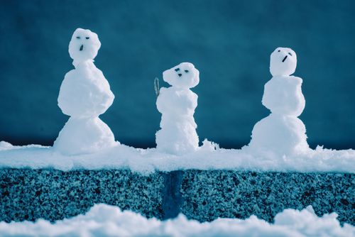 Free Charming trio of small snowmen on a snowy wall, symbolizing winter joy and creativity. Stock Photo