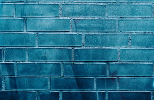 Close-up of a blue brick wall showcasing subtle graffiti textures and patterns.