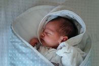 一个宁静的新生婴儿在室内舒适的蓝色圆点毛毯上平静地睡着