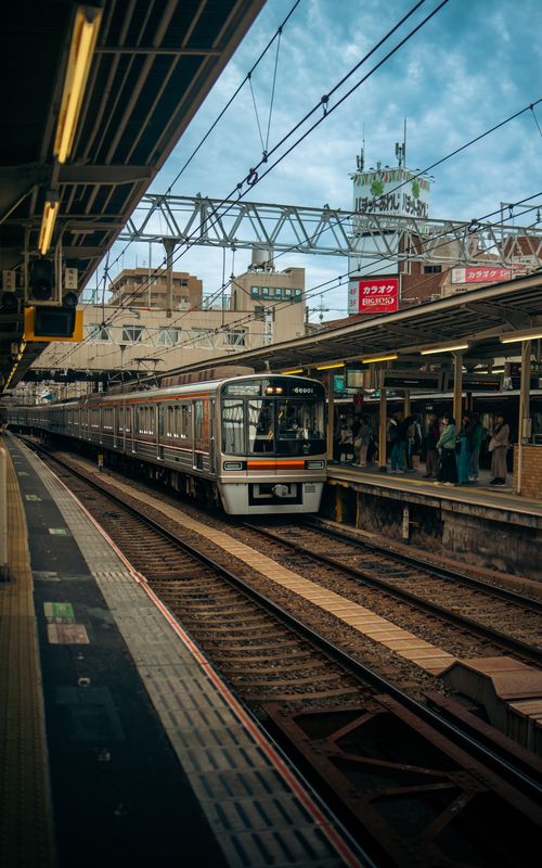 Free A bustling train station in Japan showcasing an arriving train and waiting passengers. Stock Photo