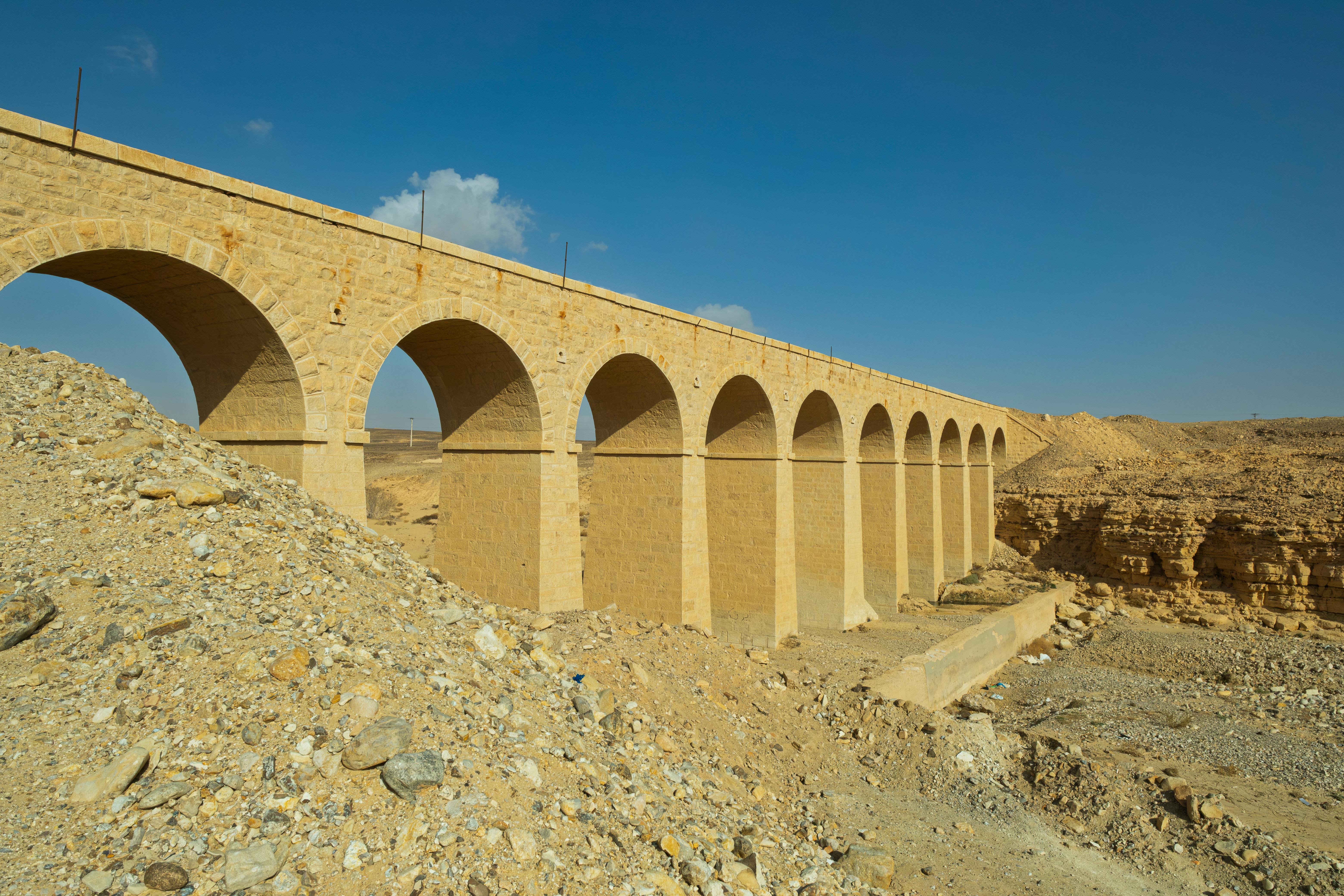 Gratis Un histórico puente ferroviario de piedra se extiende sobre el árido paisaje de Ma'an, Jordania, bajo un cielo azul claro. Foto de stock