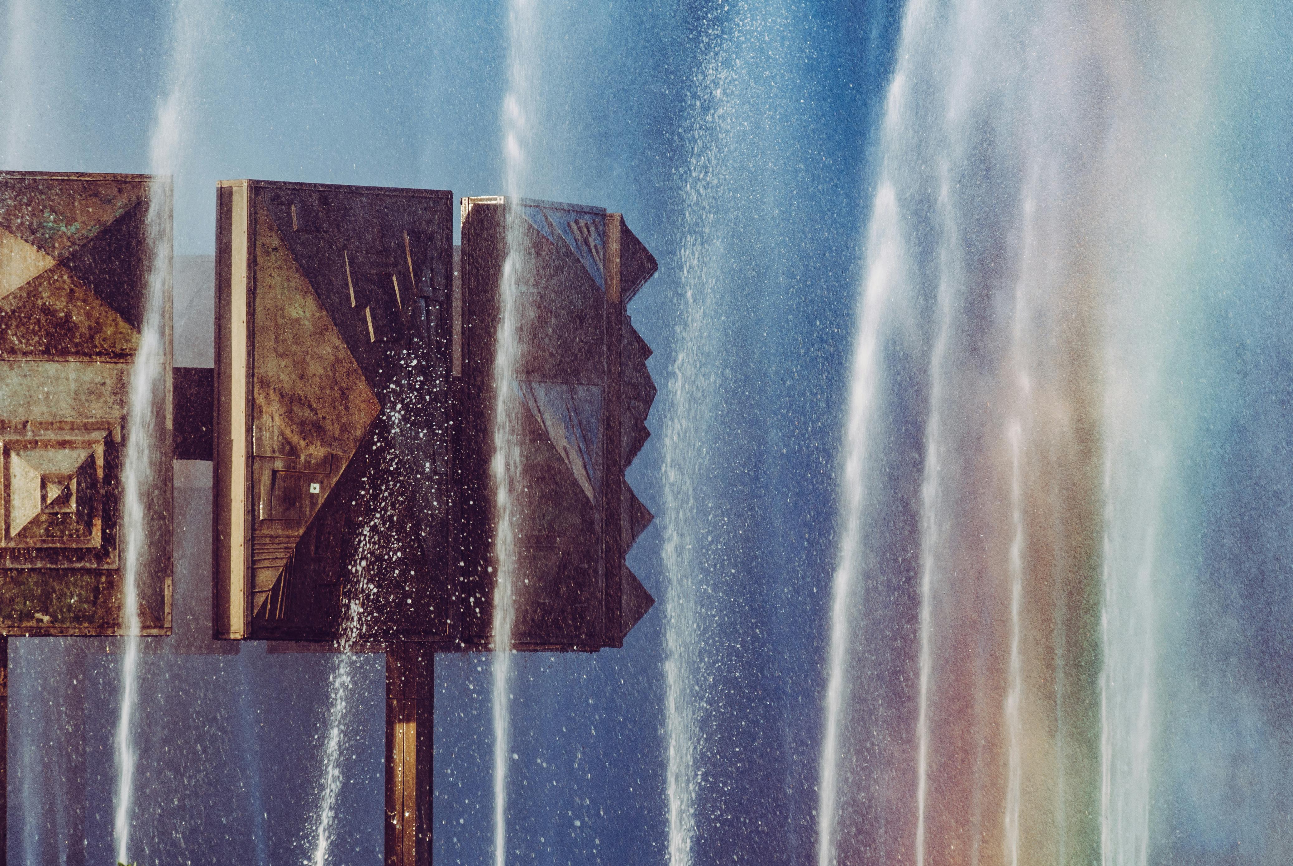 ingyenes Szivárványos árnyalatú, zúgó vízzel körülvett geometriai szerkezet művészi nézete. Stockfotó