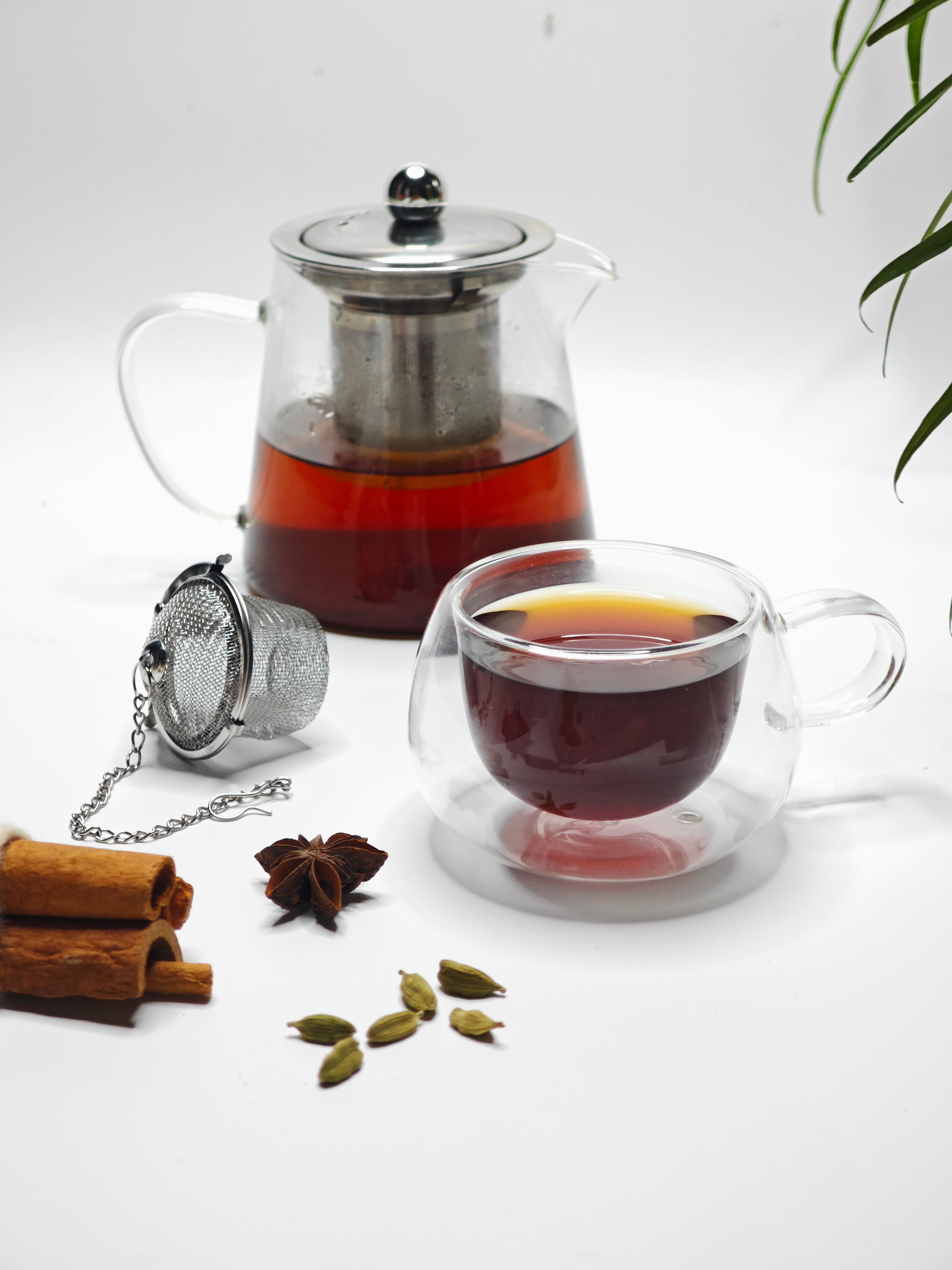 Glass teapot and teacup with spices on white background. Modern and minimalist tea setup.