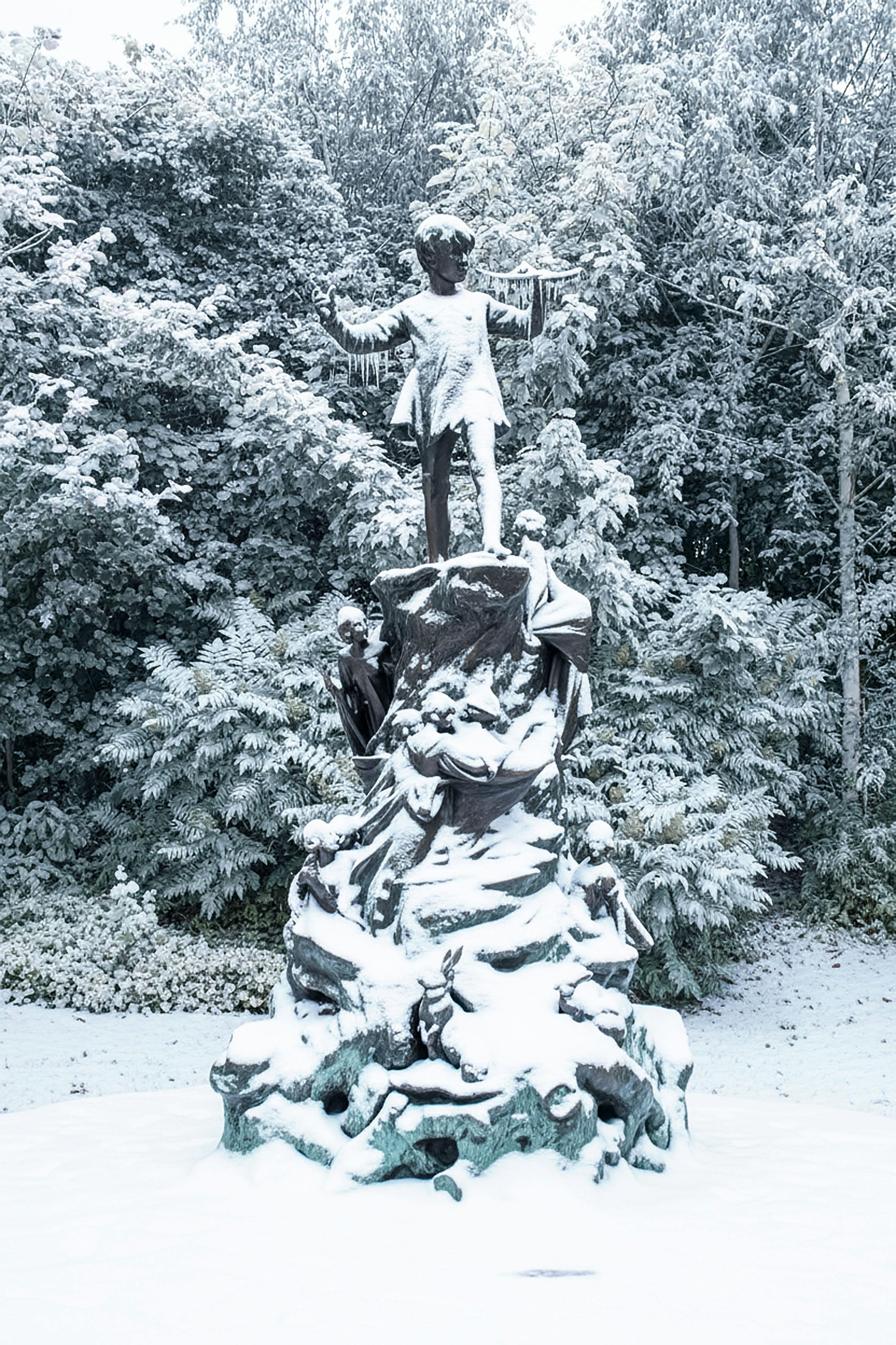 De franc Una vista captivadora de l'estàtua de Peter Pan coberta de neu en un serè parc boscós durant l'hivern al Regne Unit. Foto d'estoc