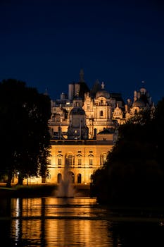 Stunning night view of an illuminated historical building reflected in a lake, located in London, UK.