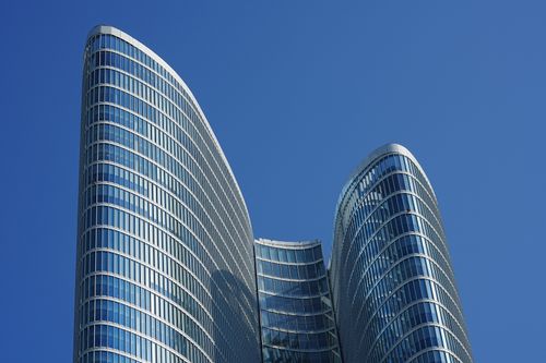 Free A striking view of a modern skyscraper in Dubai with a clear blue sky backdrop. Stock Photo