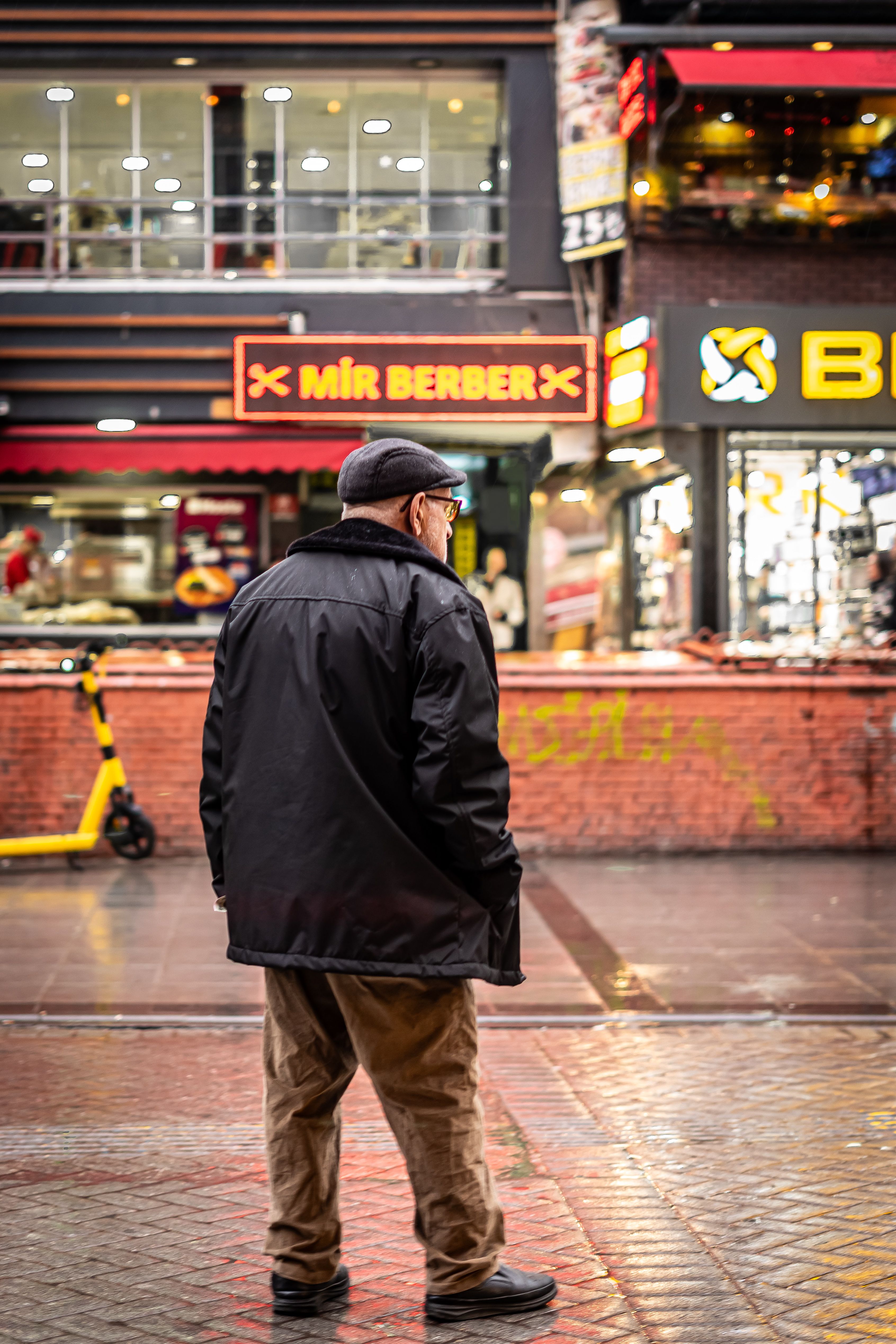 An elderly man walks down a colorful city street, capturing urban vibrancy and modern lifestyle.