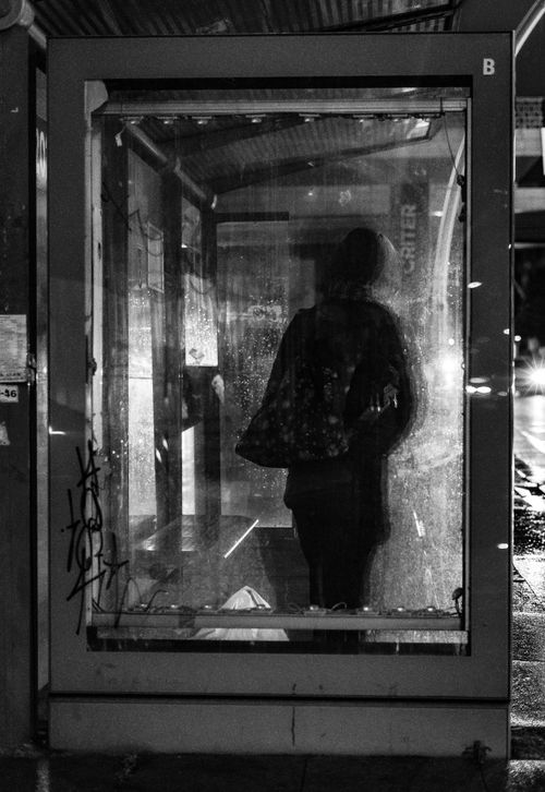 Free Person's silhouette in a rainy bus stop at night, creating an atmospheric scene. Stock Photo