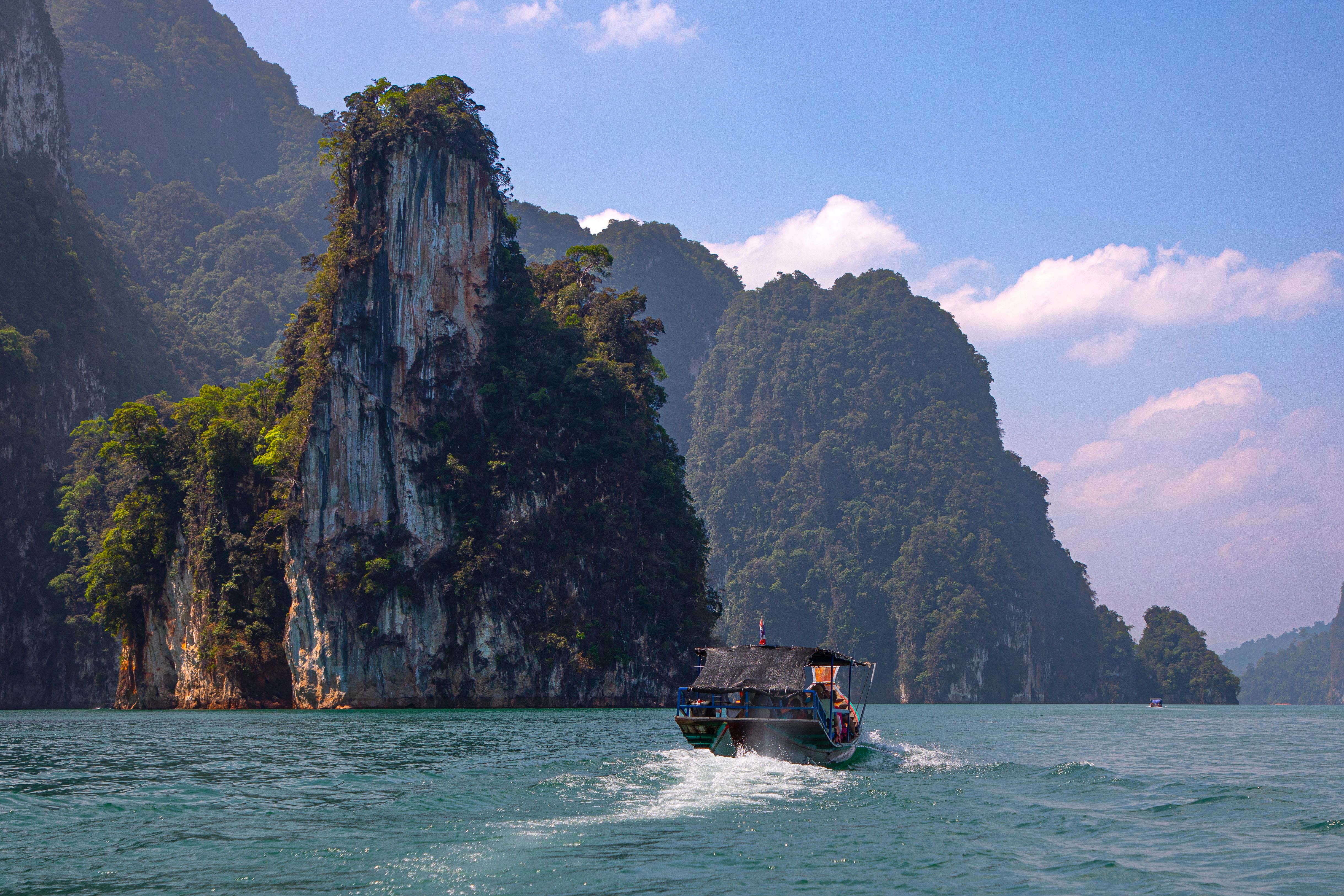 A scenic view of a longtail boat on Cheow Lan Lake in Khao Sok National Park, Thailand.