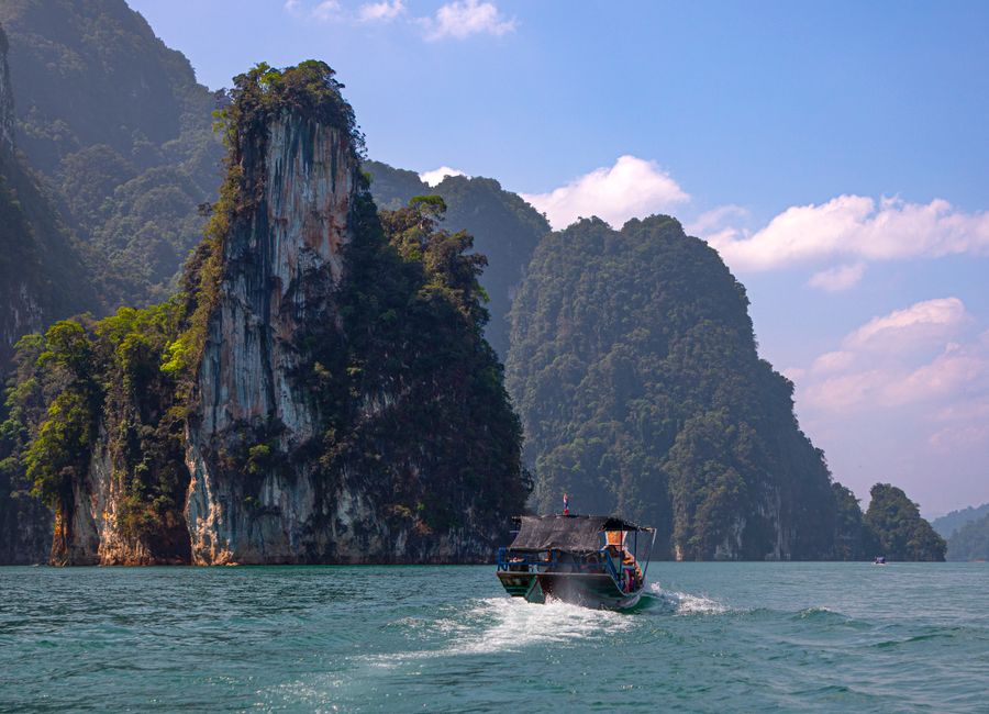 A scenic view of a longtail boat on Cheow Lan Lake in Khao Sok National Park, Thailand.