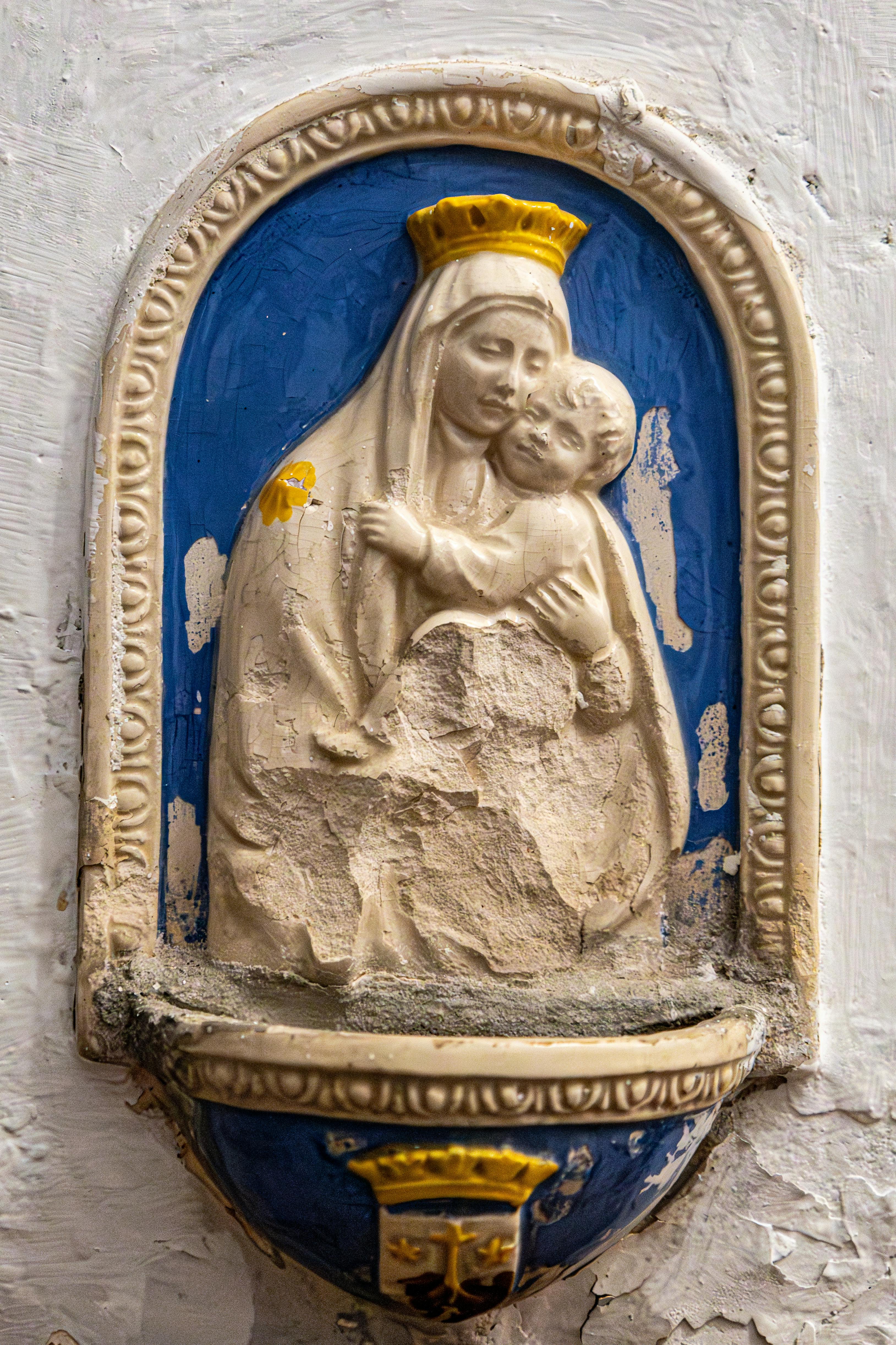 ingyenes Madonna és gyermek kopott szobra régi gipszkarton falon. Stockfotó