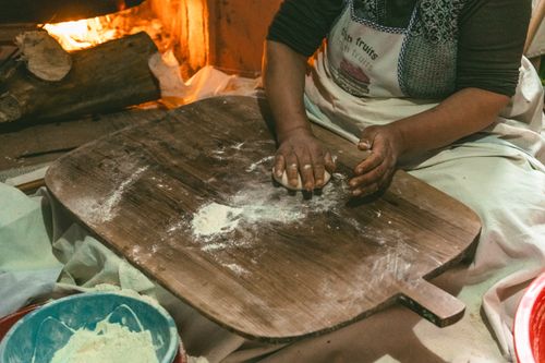 Free A person prepares traditional Turkish flatbread dough near a cozy fireplace indoors. Stock Photo