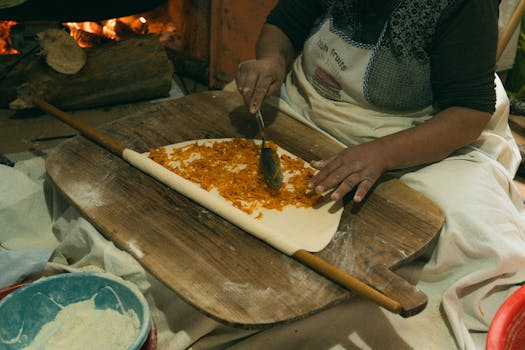 Woman prepares traditional Turkish borek with filling on dough indoors.