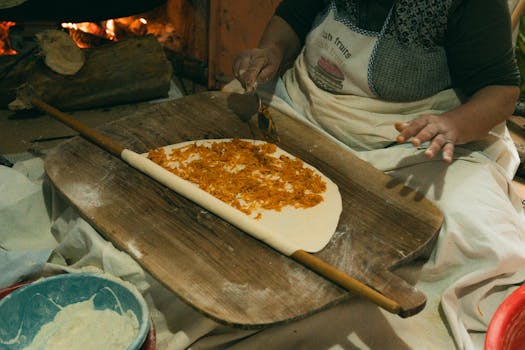 A woman prepares traditional Turkish pastry with a rolling pin indoors.