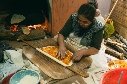 Free Woman preparing traditional Turkish bread near a wood-fired oven. Authentic culinary scene. Stock Photo
