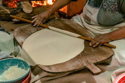 A close-up of traditional Turkish flatbread being prepared by hand in a cozy kitchen setting.