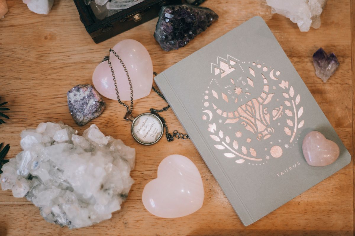 Caderno sobre mesa de madeira cercado por cristais em composição espiritual e contemplativa