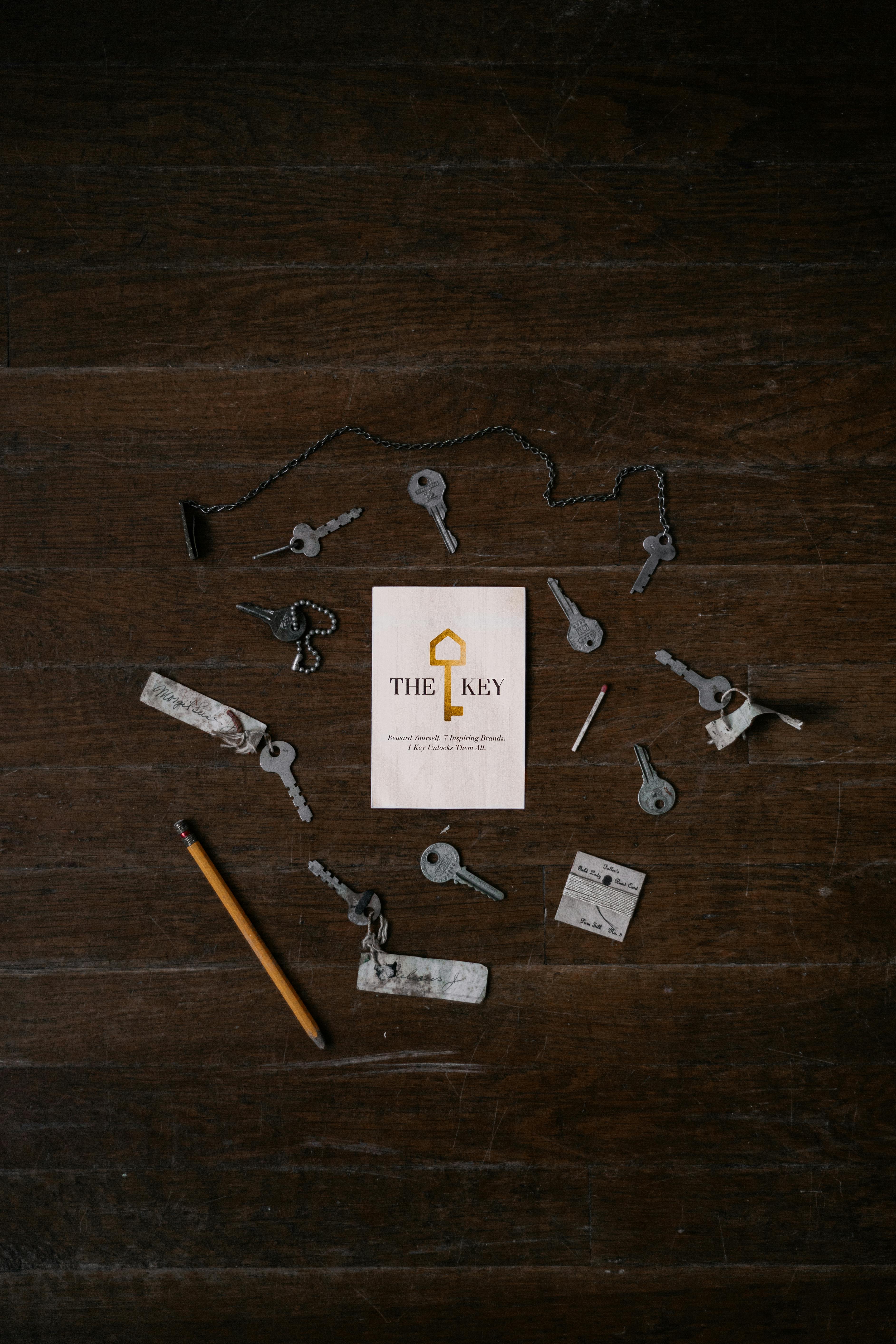 Free Top view of various vintage keys and a booklet on a dark wooden floor. Stock Photo