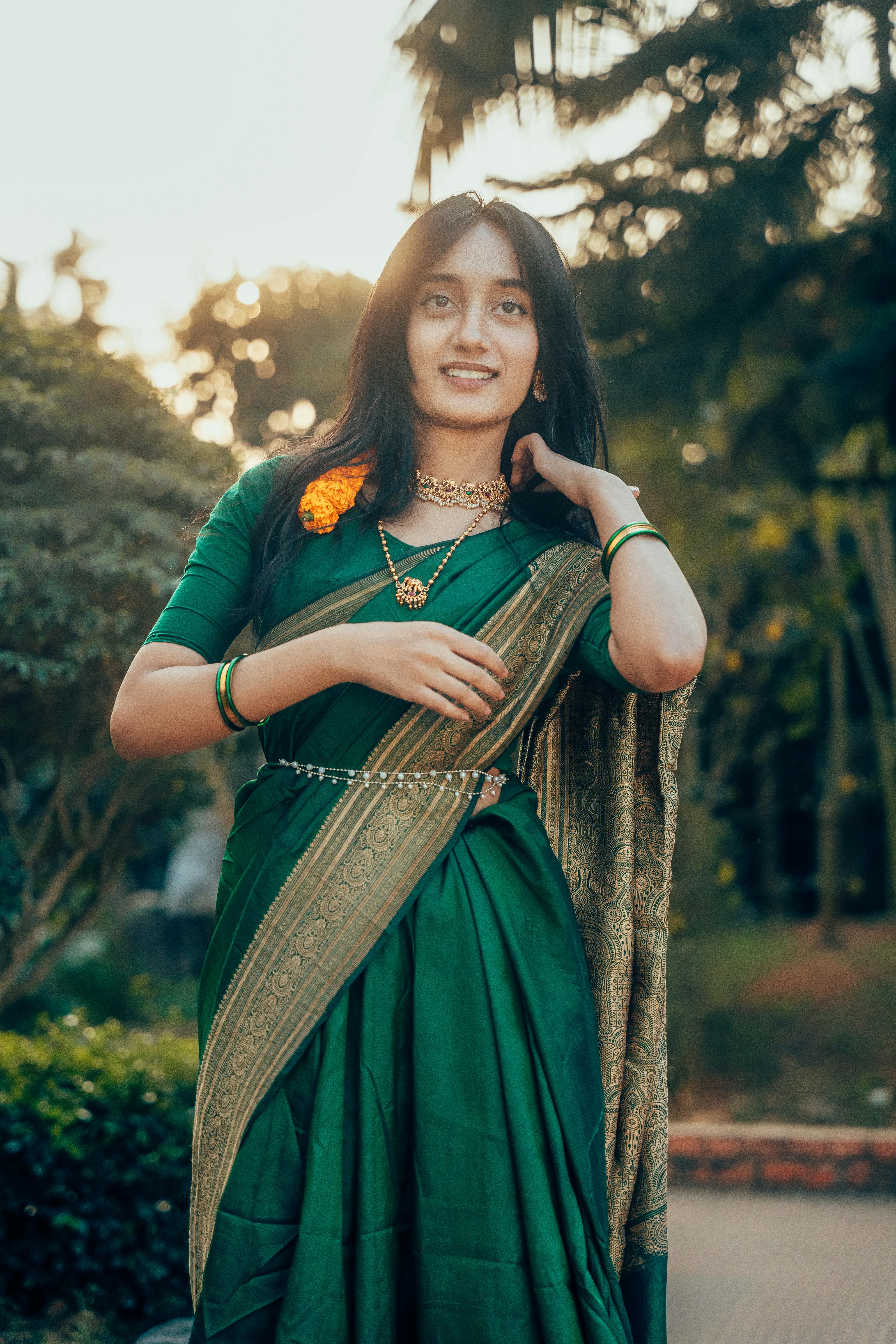 ฟรี หญิงสาวสวยในชุดสาหรีสีเขียวโพสท่าอย่างสง่างามในสวนกลางแจ้งช่วงกลางวัน คลังภาพถ่าย