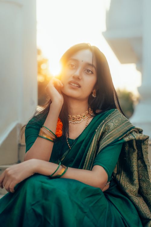 Free Stunning portrait of a young woman wearing a green saree, capturing a serene and artistic moment at sunset. Stock Photo