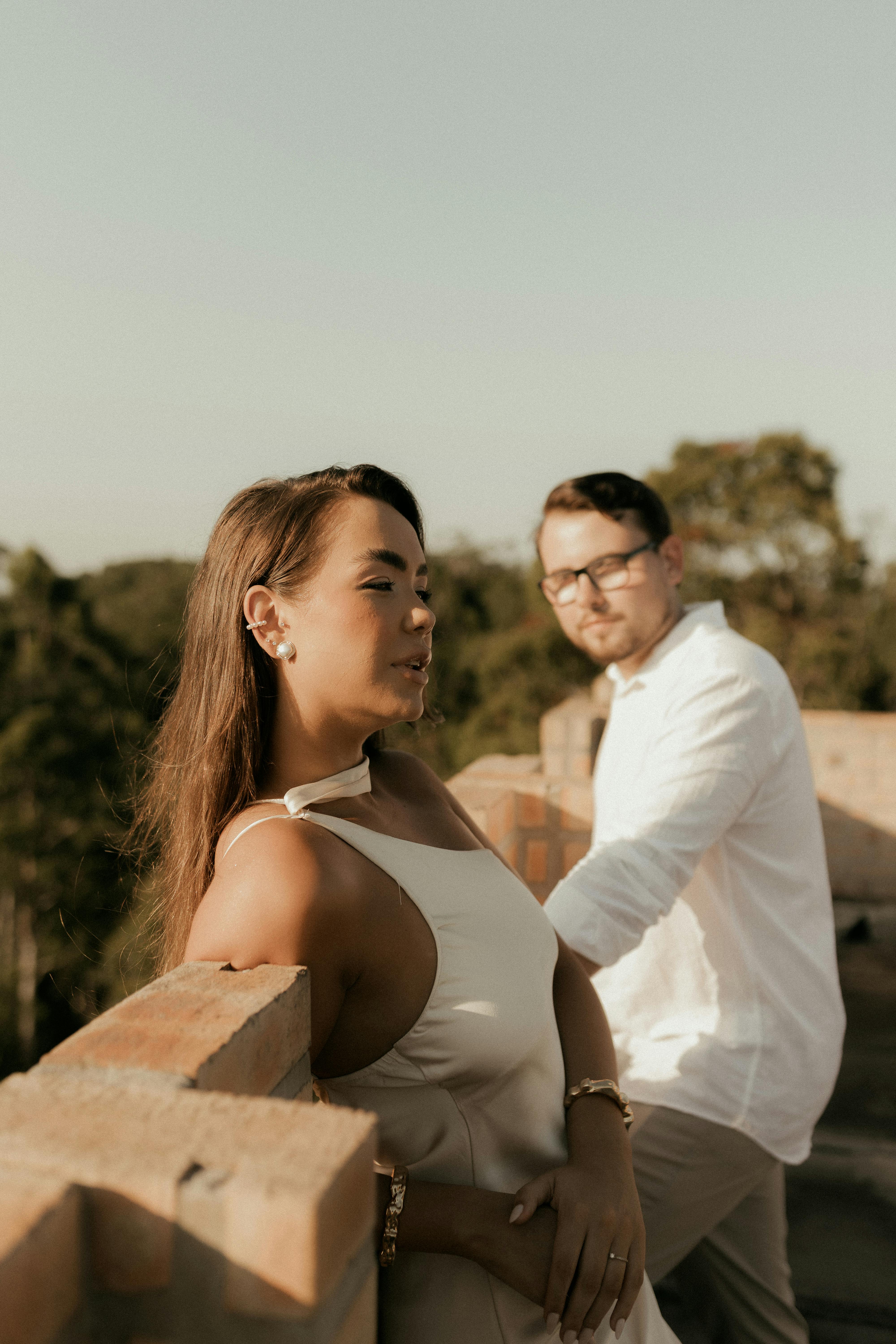 Gratis Una coppia si gode un momento di relax su una terrazza con una vegetazione lussureggiante sullo sfondo. Foto a disposizione