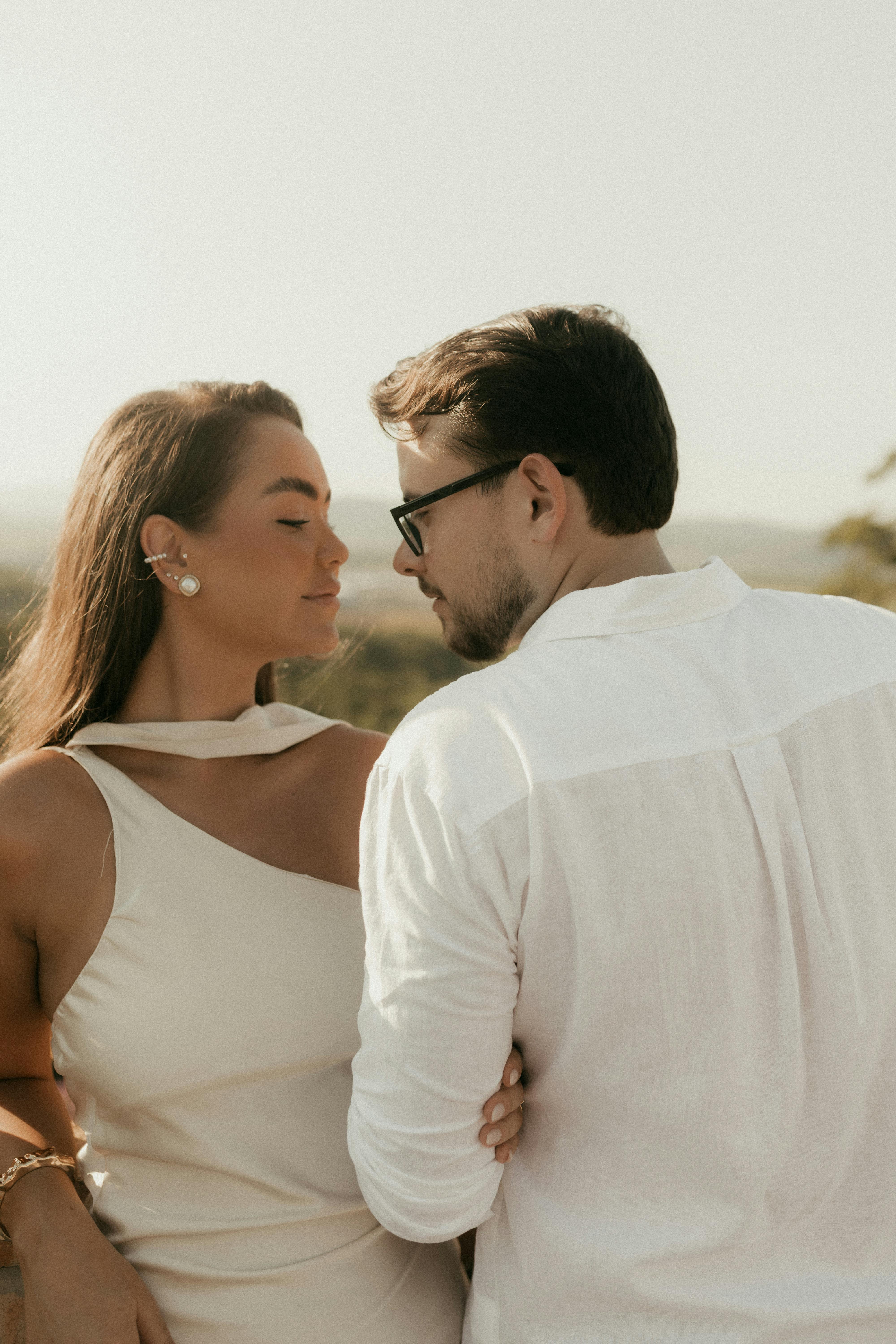 ingyenes Egy pár, akik egy gyengéd pillanatot töltenek el a szabadban naplementekor, romantikát és melegséget sugározva. Stockfotó