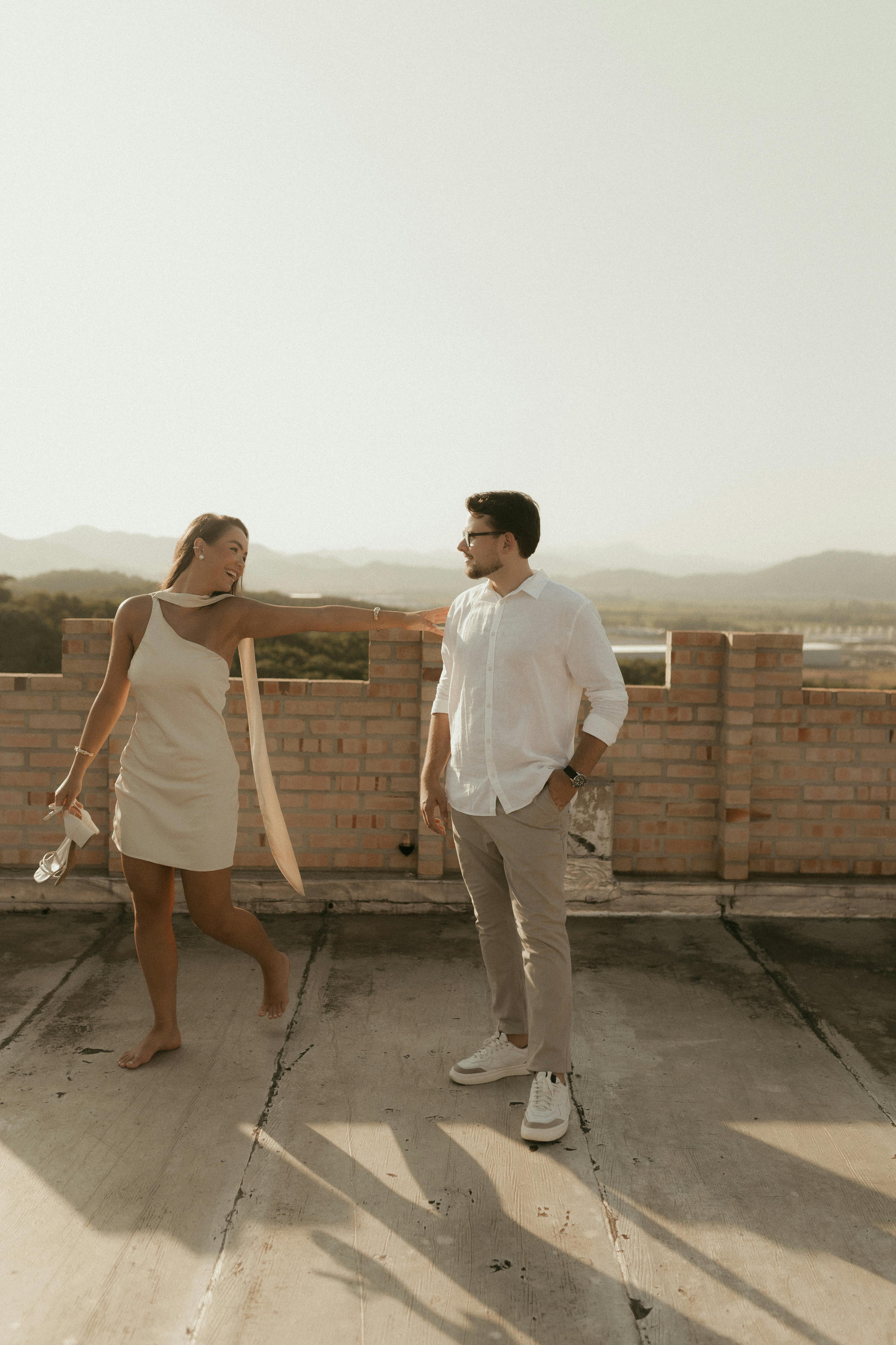 gratis Een stijlvol stel geniet van een zonnige dag op een rustiek dakterras met uitzicht op de bergen in de verte. Stockfoto