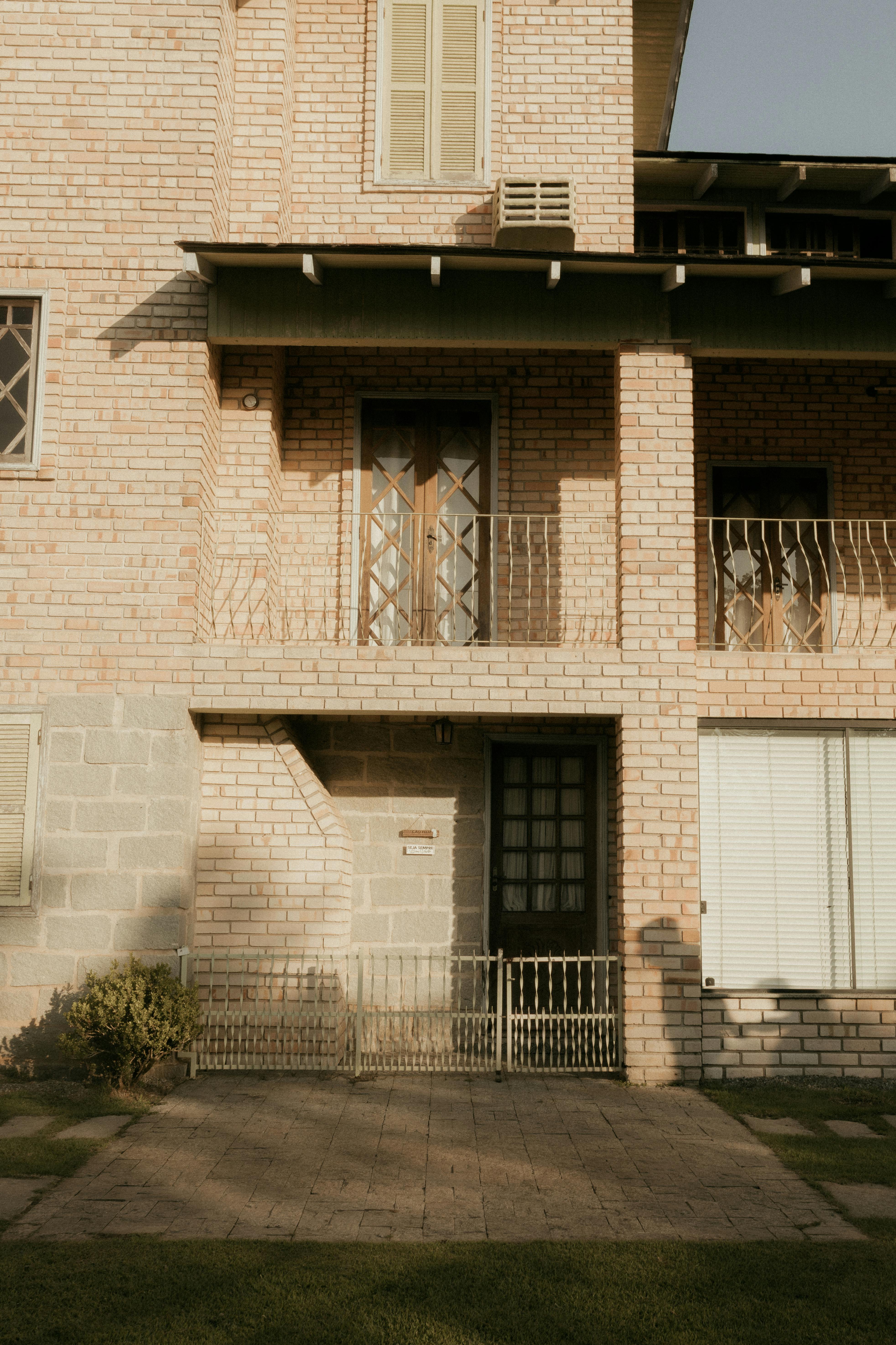 Gratis La calda luce del sole proietta ombre sulla facciata in mattoni di un'abitazione, evidenziandone i dettagli architettonici. Foto a disposizione