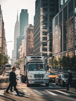 Urban scene in New York City with people crossing and skyscrapers towering.