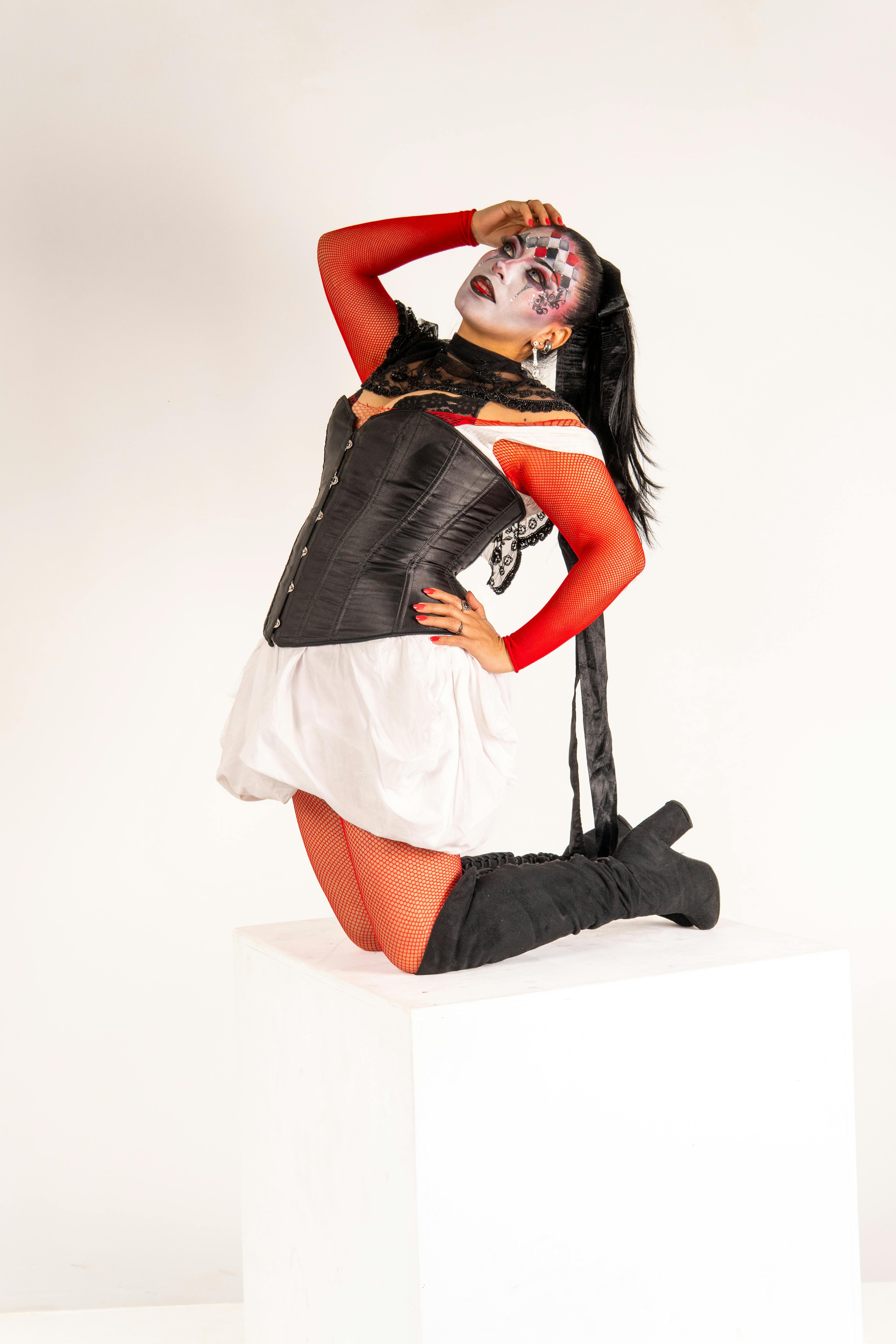 Kostenlos Lateinamerikanische Frau in Harlekin-inspiriertem Make-up und Kostüm posiert dramatisch in einem Innenraum. Stock-Foto