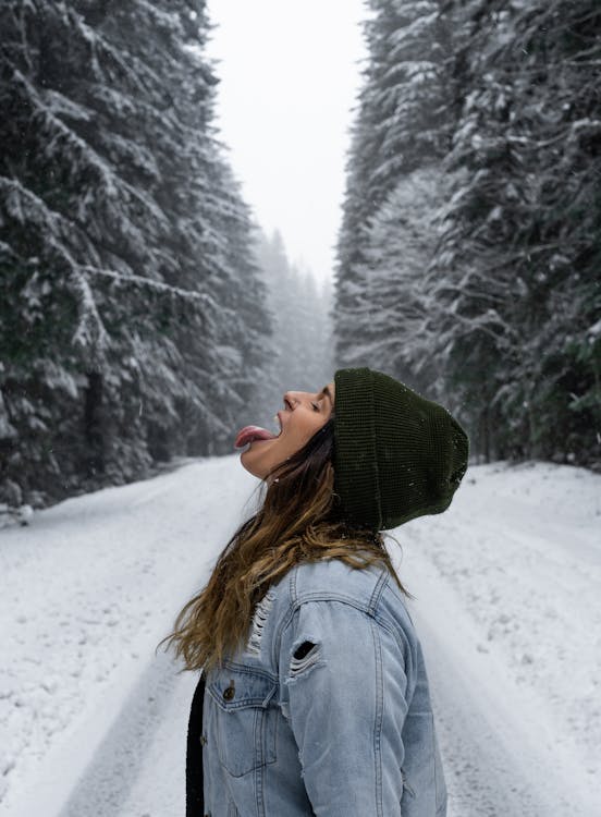Free Woman in Gray Jacket Standing on Snow Covered Ground Stock Photo