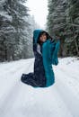 Woman in Black Jacket and Blue Scarf on Snow Covered Ground