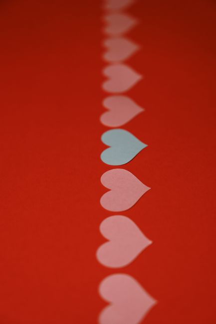 A creative arrangement of paper hearts on a vibrant red background, symbolizing love and romance.