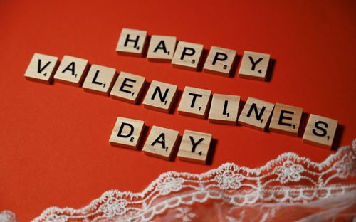 Free Wooden tiles spelling 'Happy Valentine's Day' on vibrant red background with lace detail. Stock Photo