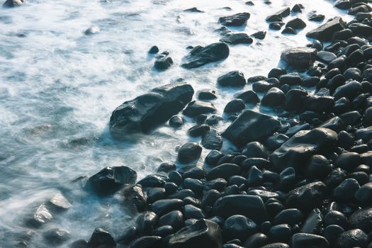 Beautiful long exposure of rocky coast with gentle waves in Madeira, Portugal.
