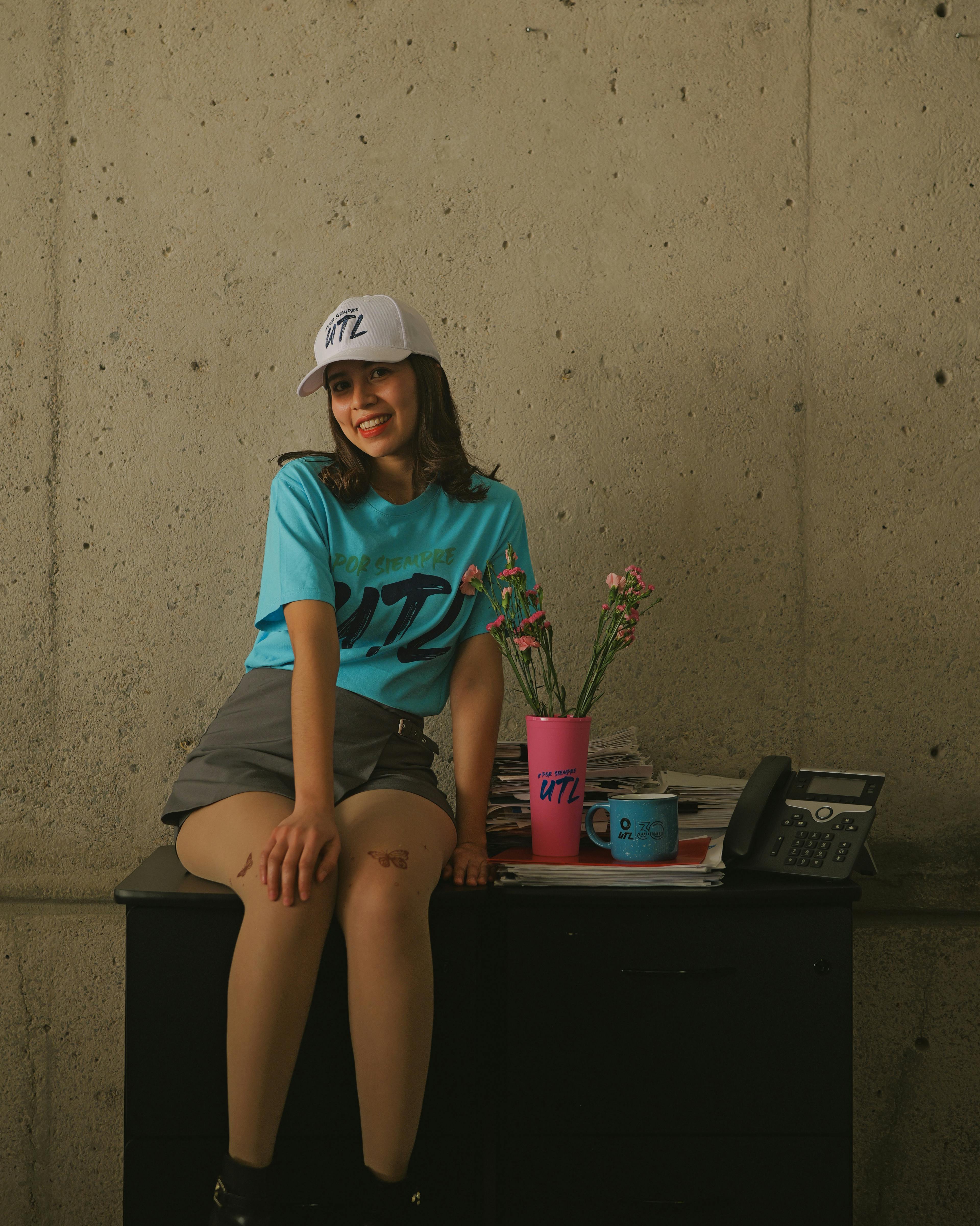 gratis Een opgewekte vrouw zit aan een bureau met bloemen en een telefoon, in een informele kantooromgeving. Stockfoto