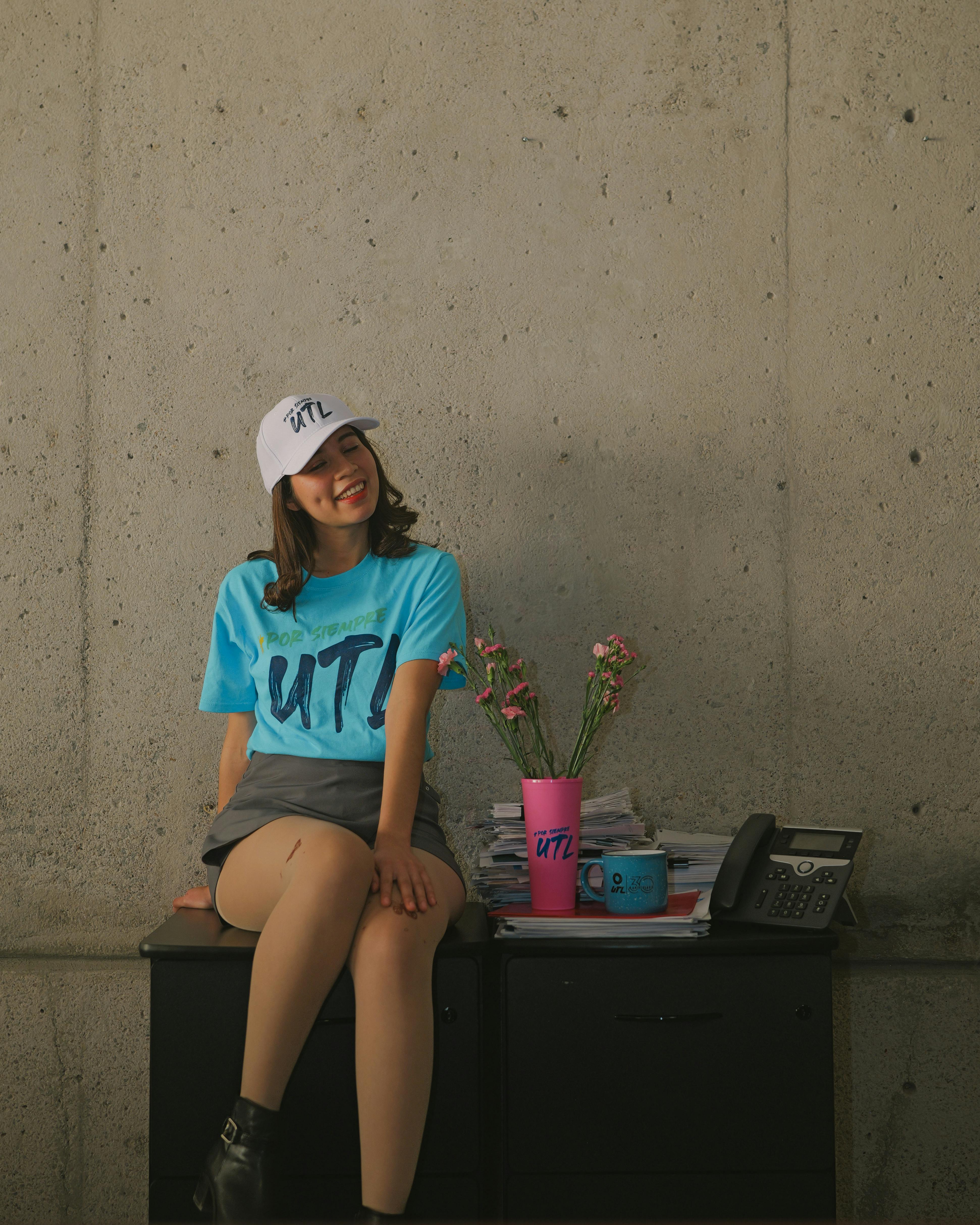 Free Young woman in bright attire seated indoors, exuding casual university vibe. Stock Photo