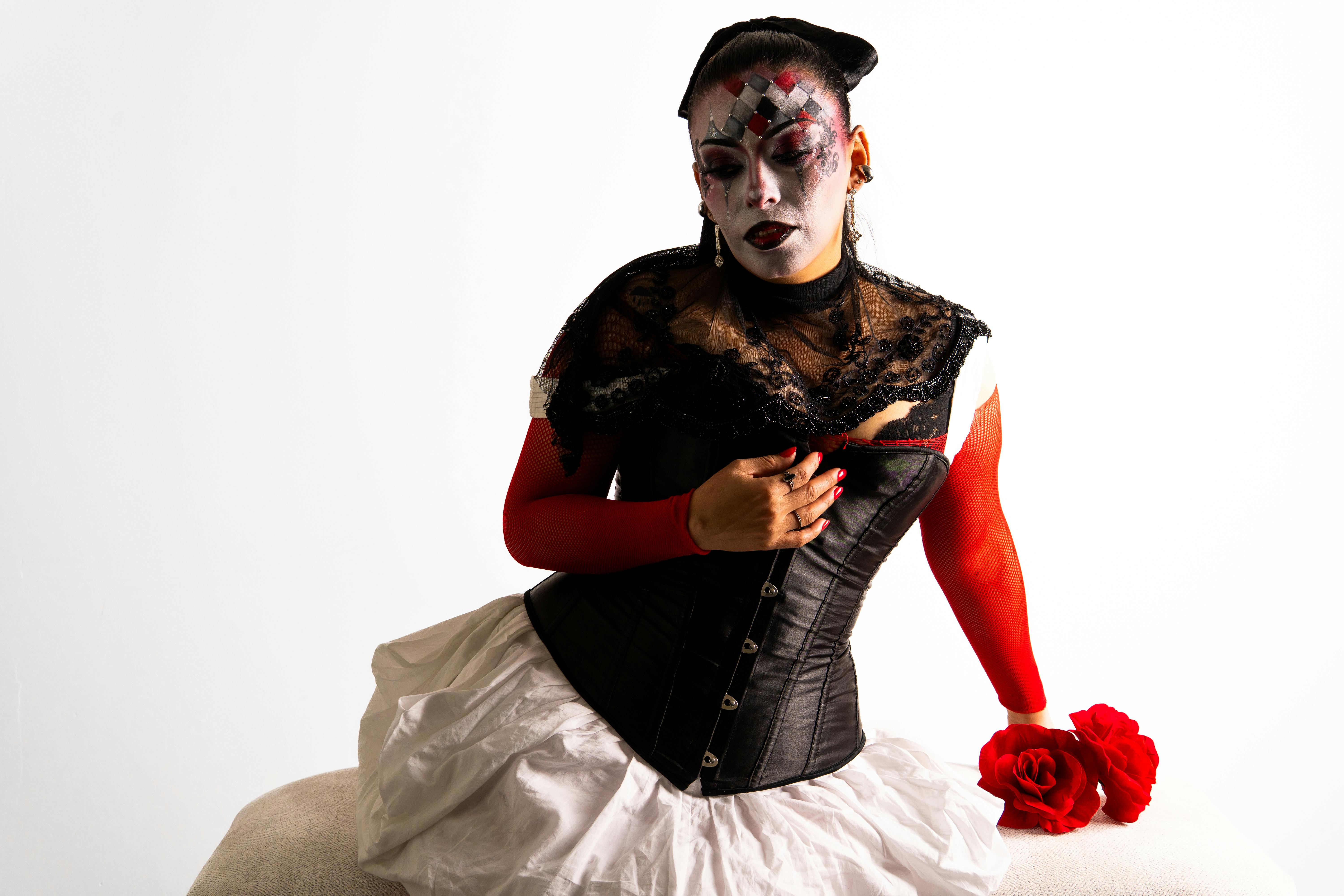 ingyenes Művészi portré egy nőről harlekin ihlette sminkben és jelmezben, piros és fekete színekkel. Stockfotó