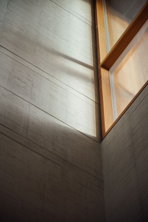 Free Sunlight streaming through a modern window in a Madrid building, casting shadows on concrete walls. Stock Photo