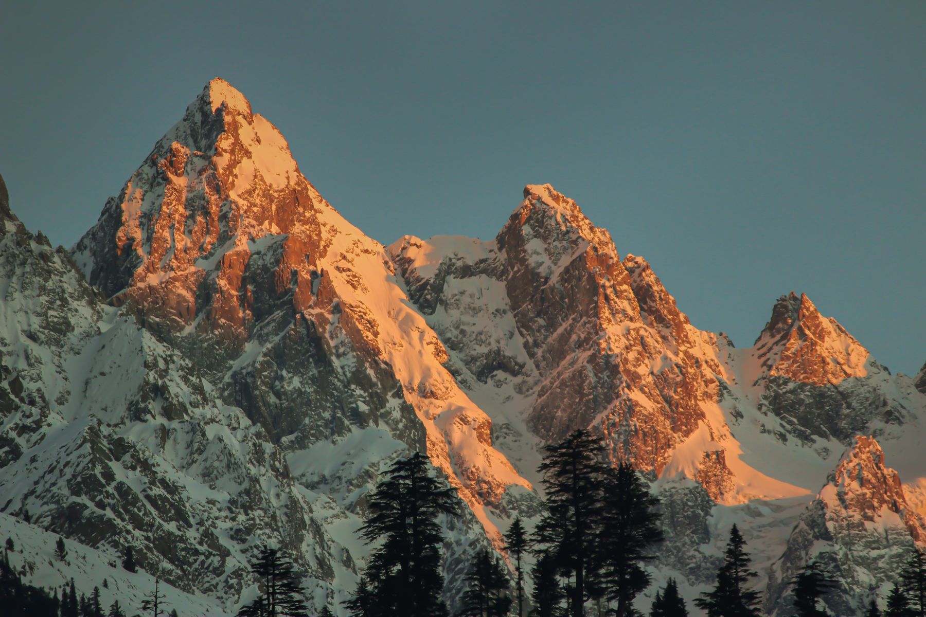 Scenic view of snow-covered mountains in Kalam, Pakistan, illuminated by sunset light.