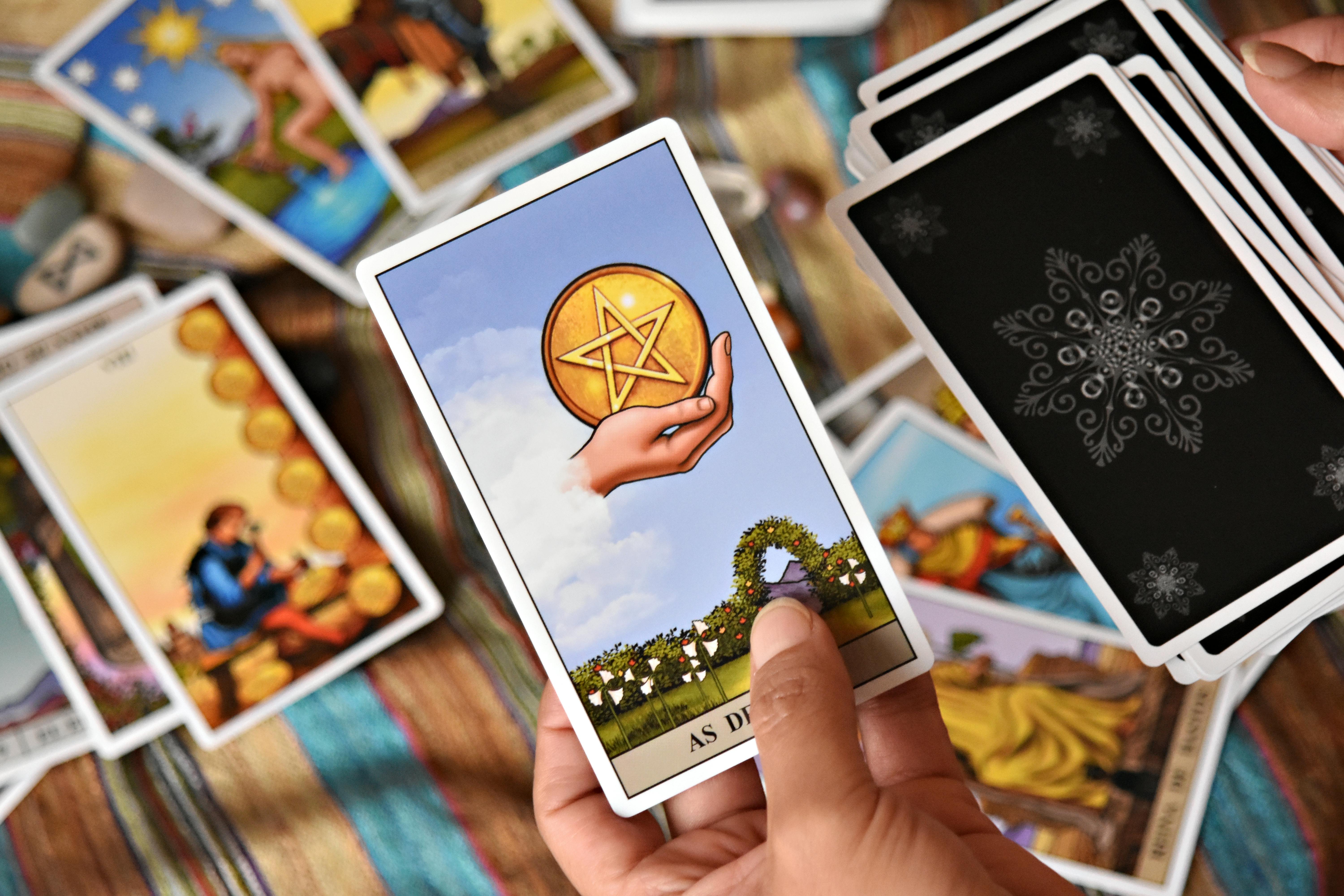 ingyenes Egy személy színes környezetben tart tarot kártyákat, jóslási eszközöket és szimbólumokat bemutatva. Stockfotó
