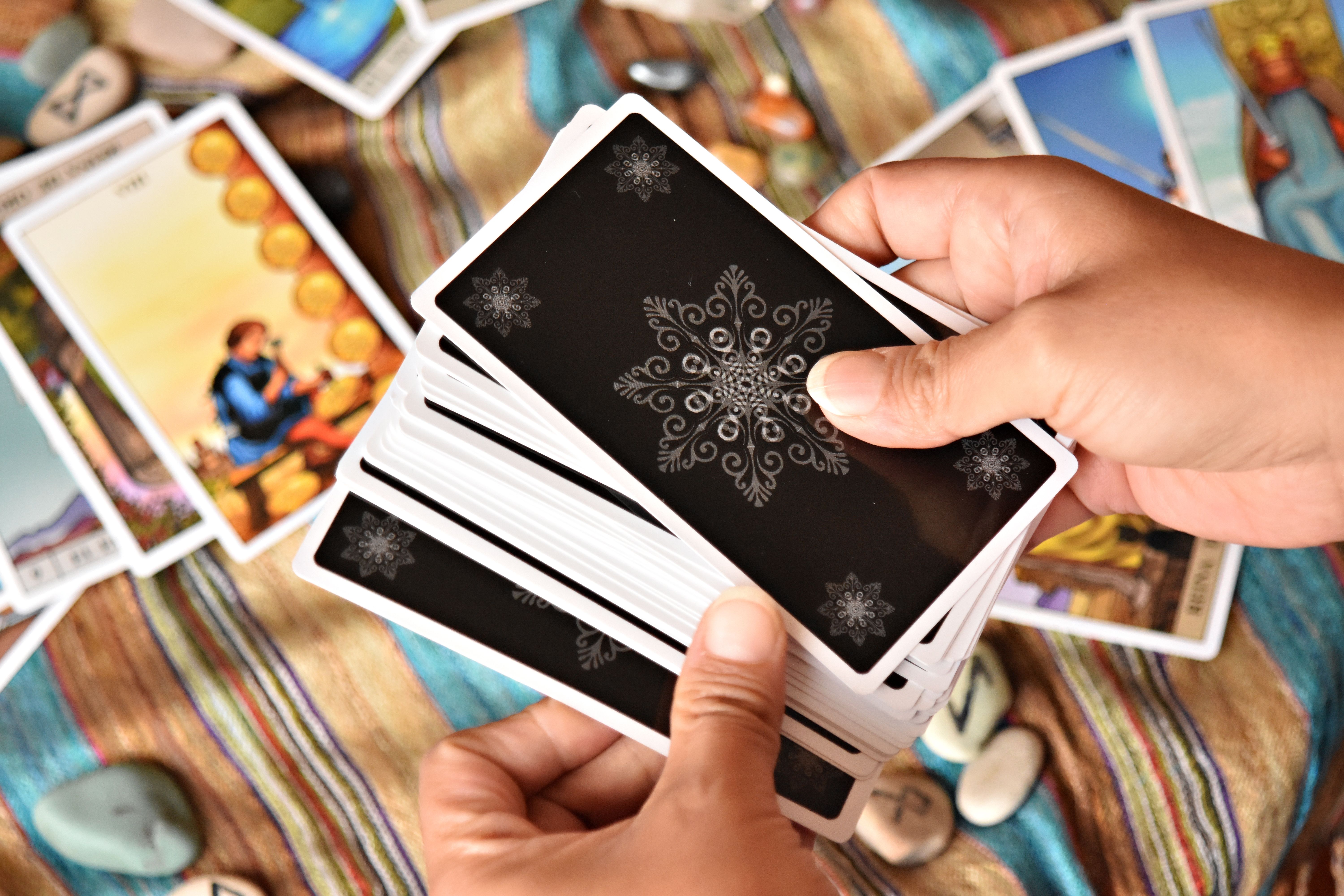 A person shuffling tarot cards, hands covering the deck, with a focused expression and soft background lighting