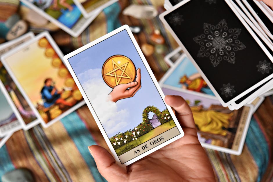 A hand holding the Ace of Pentacles tarot card during a reading on a colorful surface.