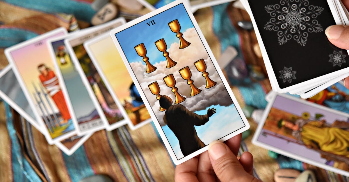 Close-up of a person holding tarot cards with a focus on the Seven of Cups card.