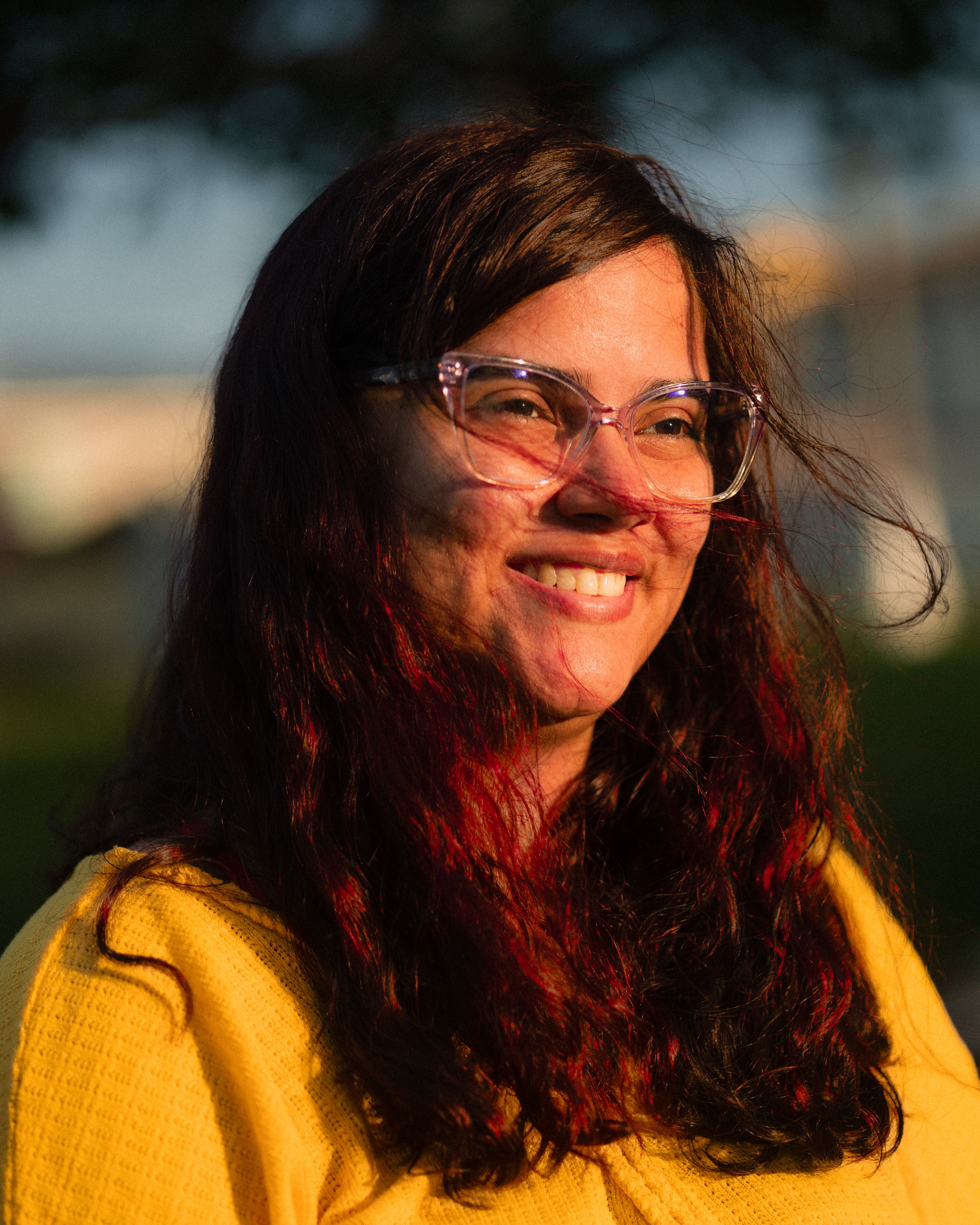 Portrait of a smiling woman with glasses captured during golden hour outdoors.