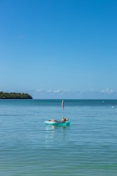 Serene scene of a woman relaxing on a raft in turquoise waters of Cabo Rojo, Puerto Rico.